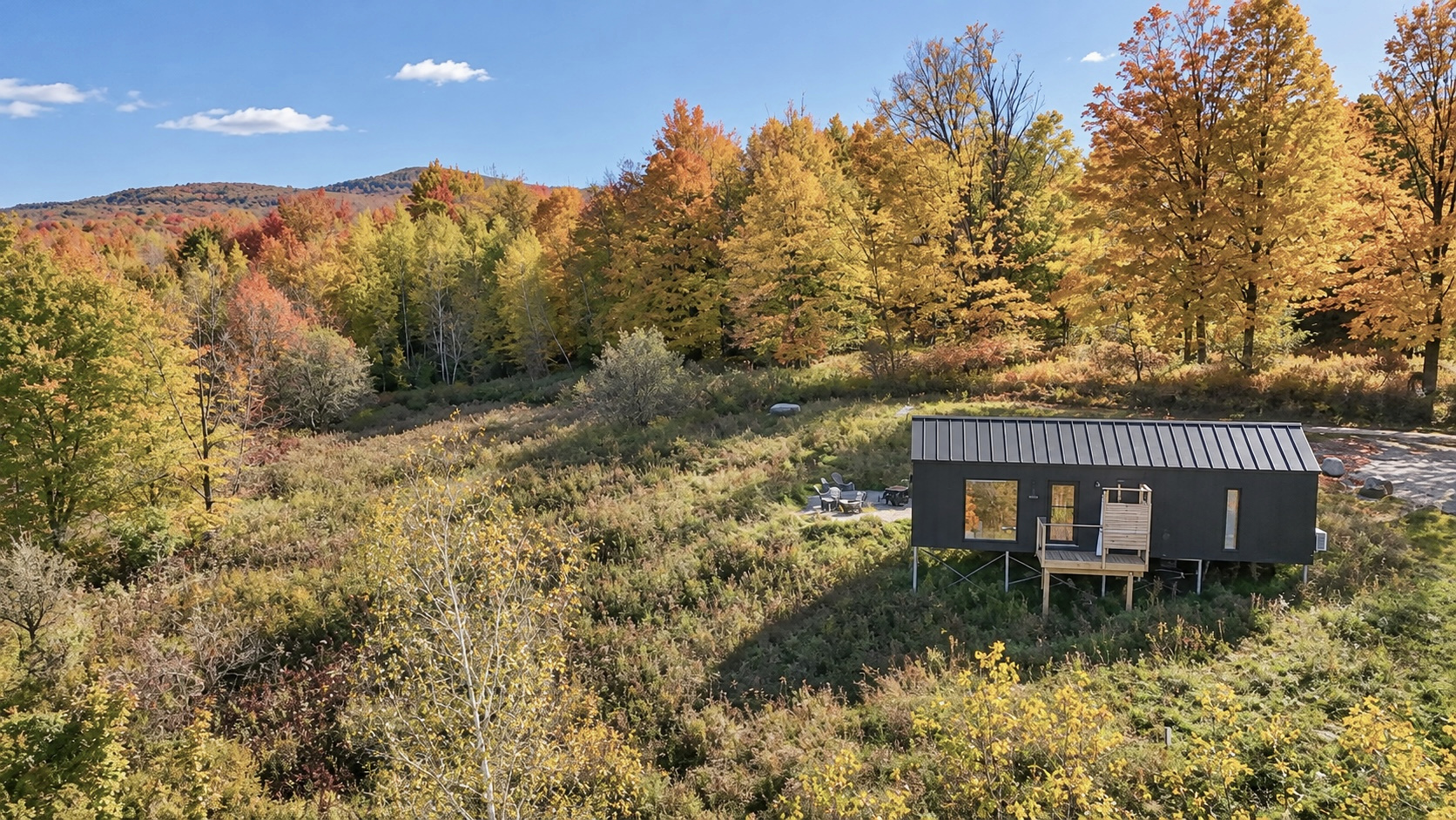Maison Roméo beneath autumn trees with a mountain view